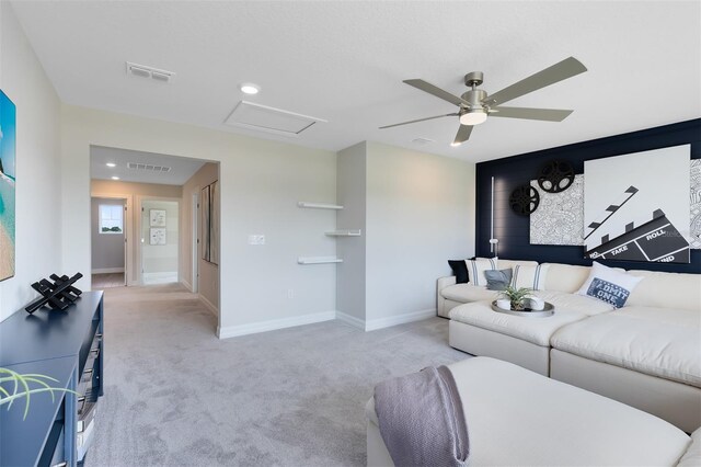 carpeted living room featuring ceiling fan, visible vents, baseboards, and attic access