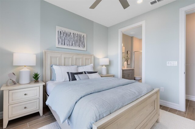 bedroom featuring wood tiled floor, baseboards, ensuite bath, and visible vents