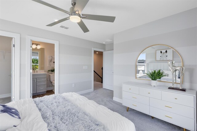 bedroom with baseboards, ensuite bathroom, light carpet, and visible vents