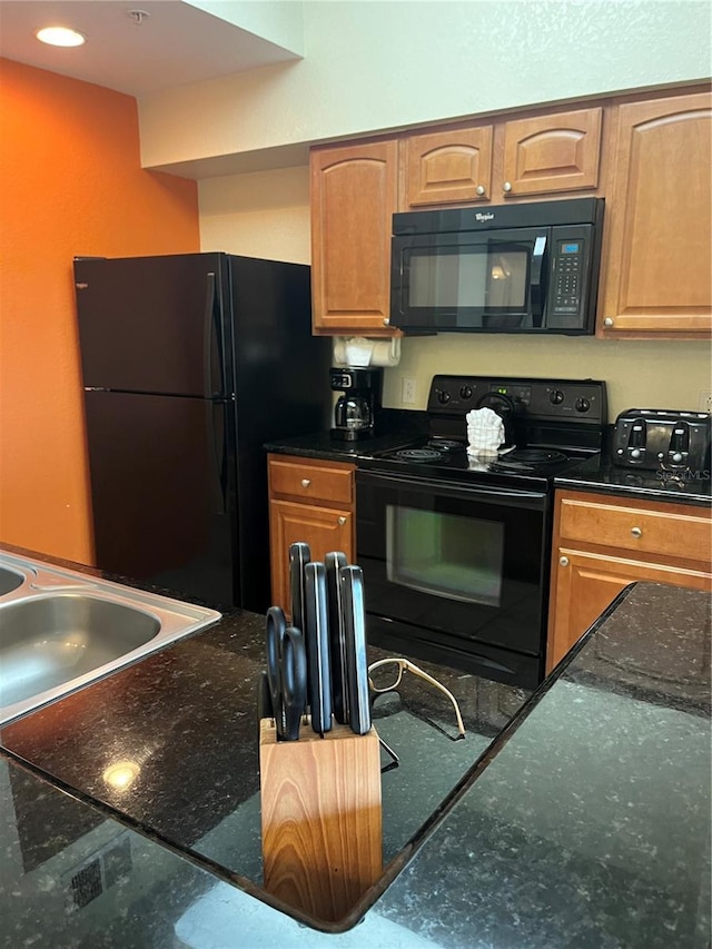 kitchen featuring a sink, dark stone counters, brown cabinets, and black appliances