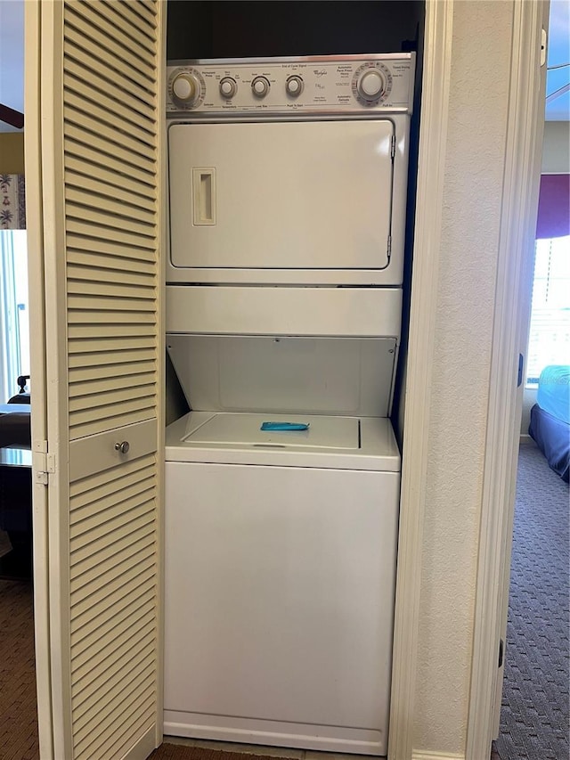 clothes washing area with laundry area, carpet, and stacked washer / dryer