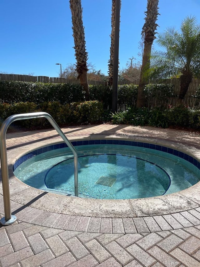 view of swimming pool with a hot tub and fence
