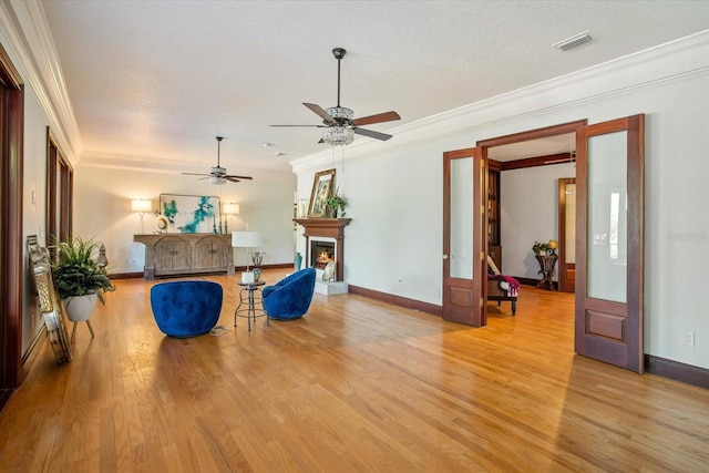 2828 Marquesas Ct, Windermere, FL 34786 - living room featuring crown molding, light wood-type flooring, ceiling fan, baseboards, and a lit fireplace
