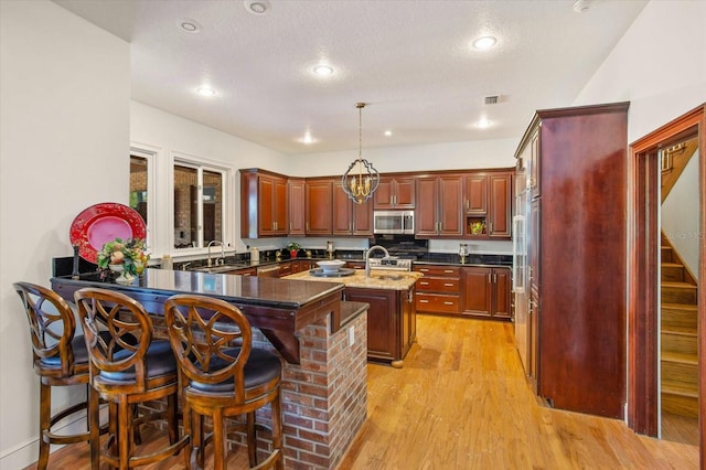 2828 Marquesas Ct, Windermere, FL 34786 - kitchen with appliances with stainless steel finishes, a sink, a center island with sink, light wood-type flooring, and a peninsula