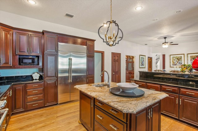 2828 Marquesas Ct, Windermere, FL 34786 - kitchen with built in appliances, a sink, a center island with sink, a textured ceiling, and light wood-style floors