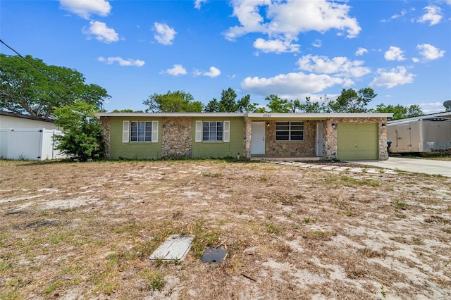 ranch-style home with fence, an attached garage, driveway, and stone siding