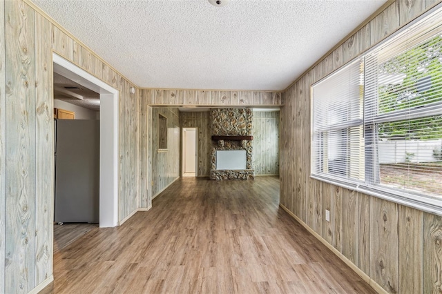 interior space with wood walls, a textured ceiling, wood finished floors, and a wealth of natural light