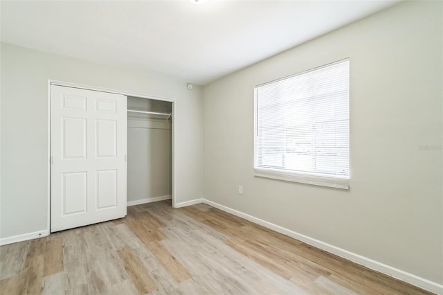 unfurnished bedroom with a closet, baseboards, and light wood-type flooring