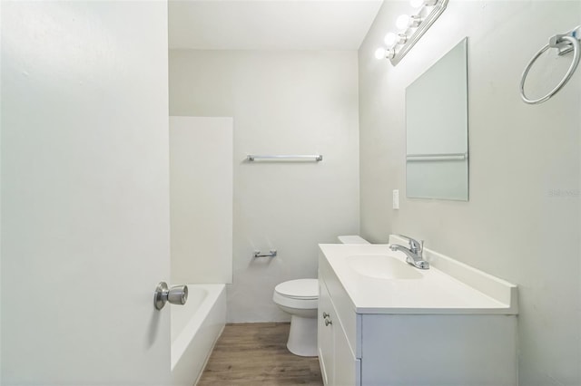 full bath featuring vanity, a bathing tub, wood finished floors, and toilet