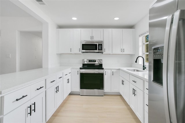 kitchen featuring a sink, stainless steel appliances, visible vents, a peninsula, and light countertops