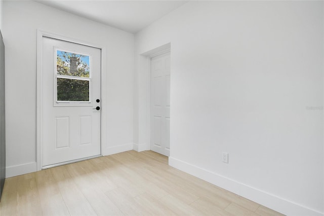 doorway to outside featuring baseboards and light wood-type flooring