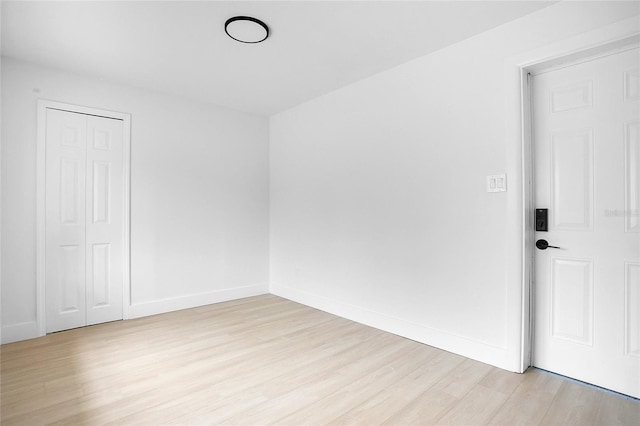 spare room with baseboards and light wood-style flooring