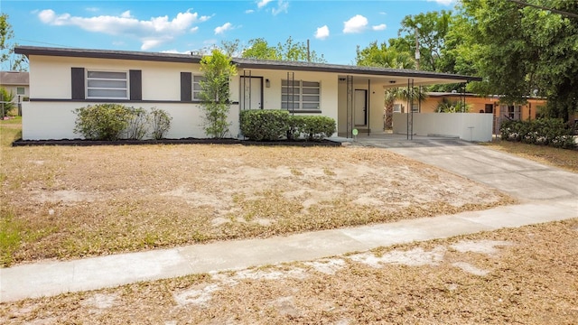 ranch-style home featuring driveway, an attached carport, and stucco siding