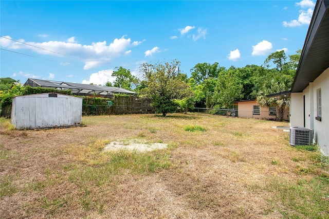 view of yard featuring cooling unit, a storage shed, an outbuilding, and a fenced backyard