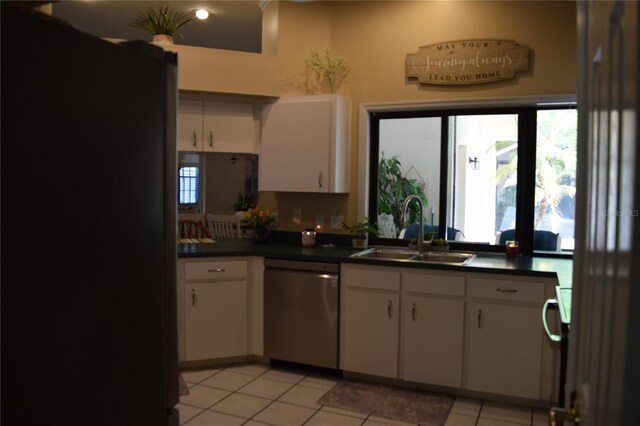 kitchen featuring dark countertops, white cabinetry, a sink, dishwasher, and light tile patterned flooring