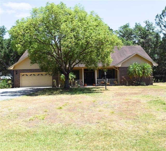 view of front of home with a front lawn, brick siding, a garage, a porch, and driveway
