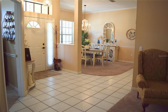 foyer featuring crown molding, light colored carpet, an inviting chandelier, and light tile patterned flooring