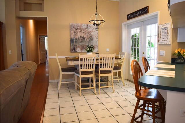 dining space featuring light tile patterned flooring, baseboards, a notable chandelier, and french doors