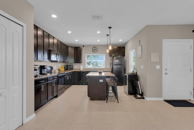 320 Primrose Dr, Davenport, FL 33837 - kitchen with black appliances, a breakfast bar area, light tile patterned floors, recessed lighting, and a kitchen island