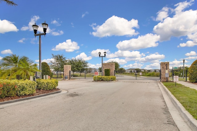 320 Primrose Dr, Davenport, FL 33837 - view of asphalt road with a gate, street lighting, a gated entry, and curbs