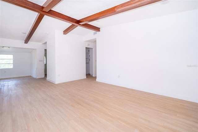 unfurnished living room featuring visible vents, lofted ceiling with beams, light wood-style flooring, and baseboards