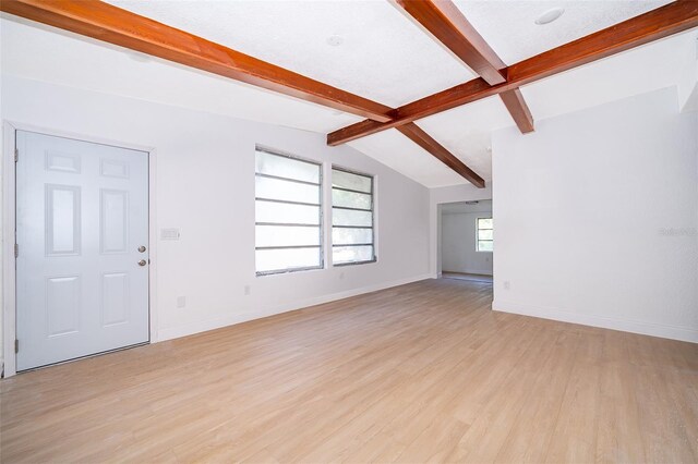 unfurnished living room featuring light wood finished floors, vaulted ceiling with beams, and baseboards