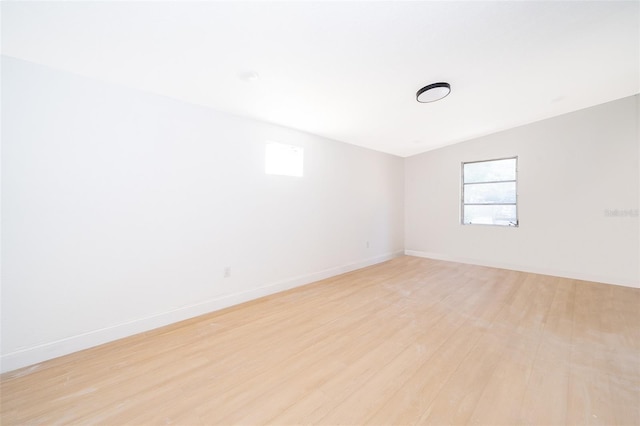 unfurnished room with baseboards, light wood-type flooring, and plenty of natural light