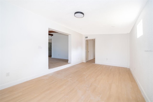 spare room featuring baseboards and light wood-type flooring