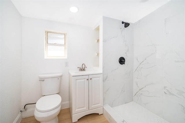 full bath featuring baseboards, a marble finish shower, toilet, wood finished floors, and vanity