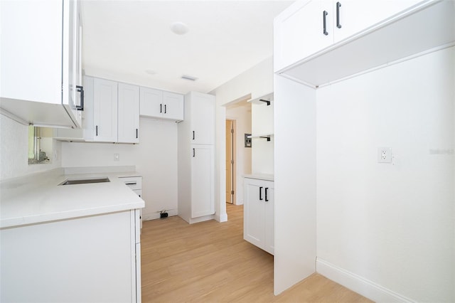 kitchen with light countertops, visible vents, white cabinets, and light wood-type flooring