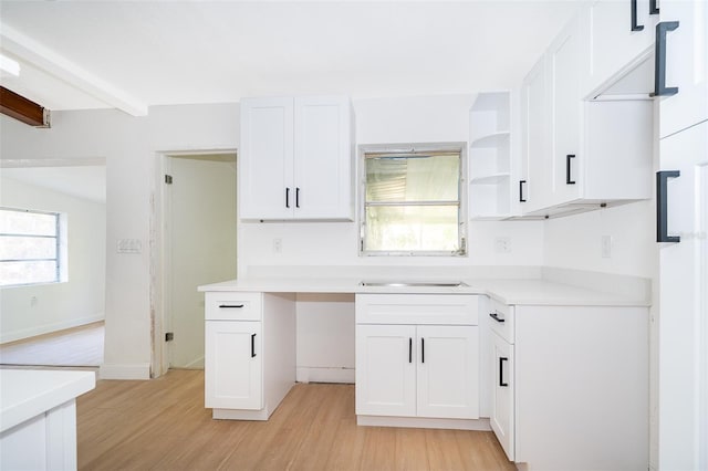 kitchen with white cabinetry, light wood-type flooring, open shelves, and light countertops