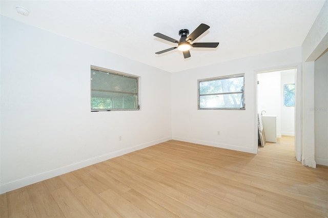 spare room with baseboards, ceiling fan, and light wood-style flooring