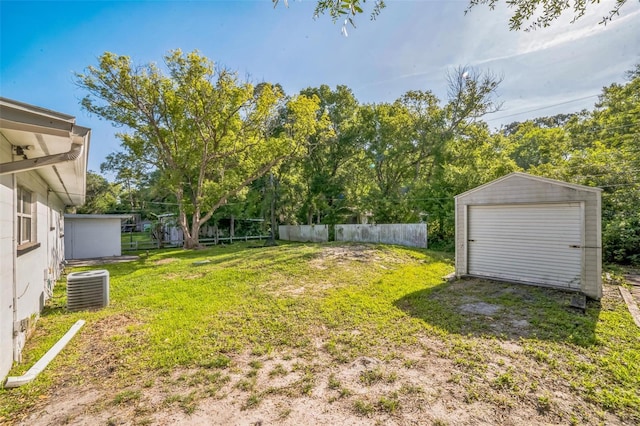 view of yard featuring an outbuilding, central AC, and fence