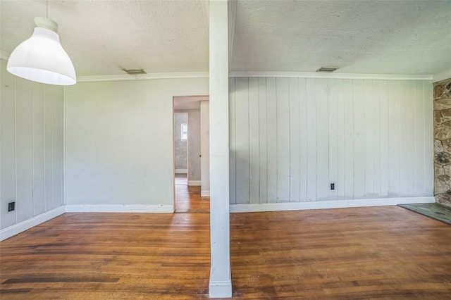 spare room featuring a textured ceiling, wood finished floors, visible vents, and baseboards