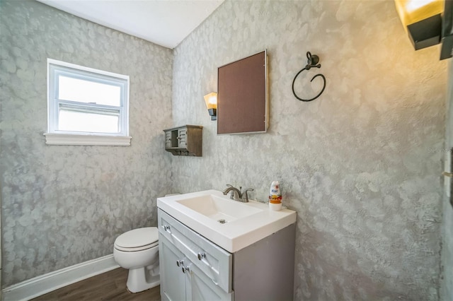 bathroom featuring baseboards, wood finished floors, toilet, and vanity
