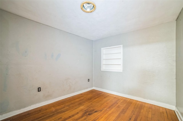 unfurnished room featuring baseboards and hardwood / wood-style flooring