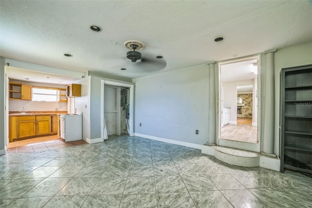 unfurnished living room with recessed lighting, a textured ceiling, a sink, and baseboards