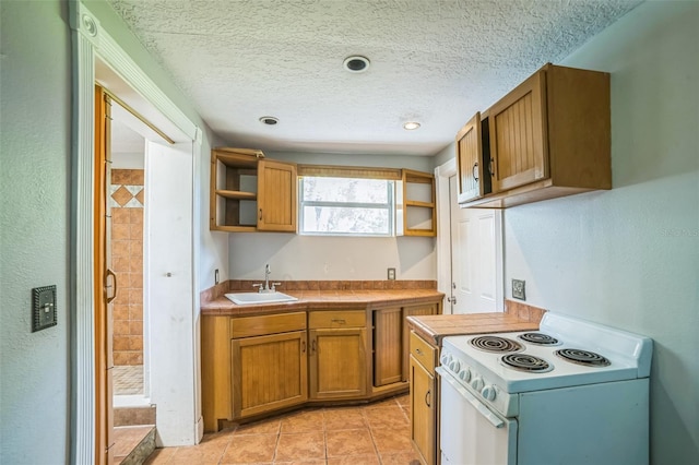 kitchen featuring electric stove, a sink, open shelves, tile countertops, and a textured ceiling