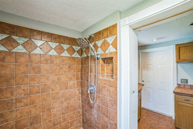 full bath with tile patterned flooring, a tile shower, and a textured ceiling