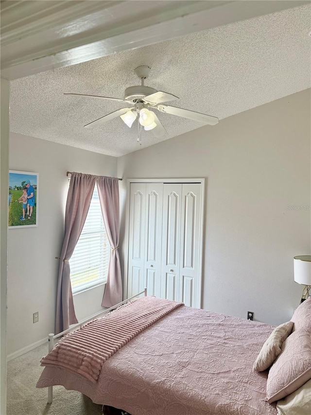 carpeted bedroom with a closet, a textured ceiling, ceiling fan, and baseboards