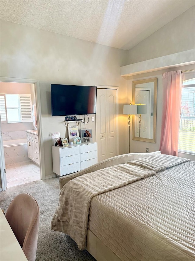 bedroom featuring a closet, lofted ceiling, light carpet, ensuite bathroom, and a textured ceiling