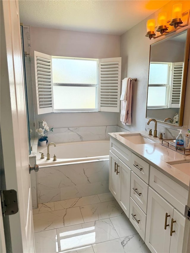 bathroom with a bath, a wealth of natural light, marble finish floor, and vanity