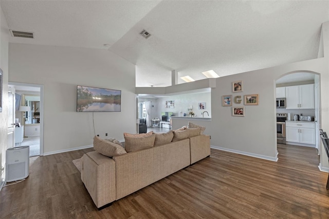 2407 Oakington St, Winter Garden, FL 34787 - living area featuring vaulted ceiling, wood finished floors, arched walkways, and baseboards