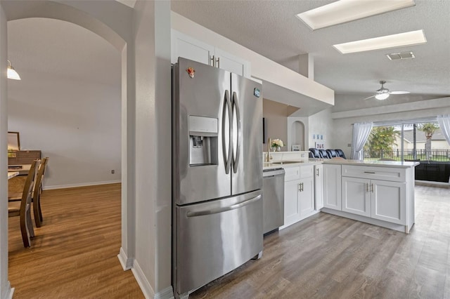 2407 Oakington St, Winter Garden, FL 34787 - kitchen with stainless steel appliances, arched walkways, white cabinets, a peninsula, and lofted ceiling