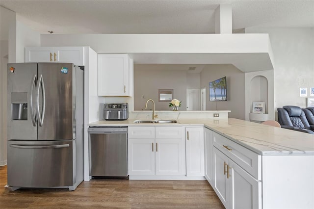 2407 Oakington St, Winter Garden, FL 34787 - kitchen featuring appliances with stainless steel finishes, a sink, a peninsula, wood finished floors, and white cabinetry