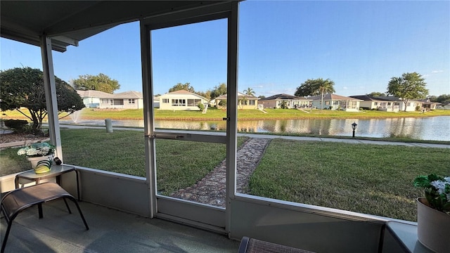 sunroom featuring a water view, a residential view, and plenty of natural light