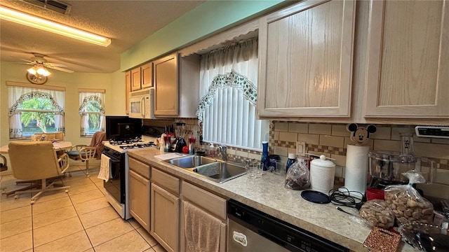 kitchen featuring white microwave, gas range oven, backsplash, dishwasher, and a sink