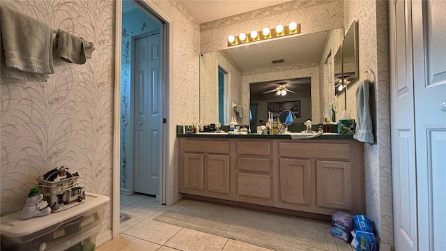 full bathroom with a closet, a ceiling fan, double vanity, visible vents, and wallpapered walls