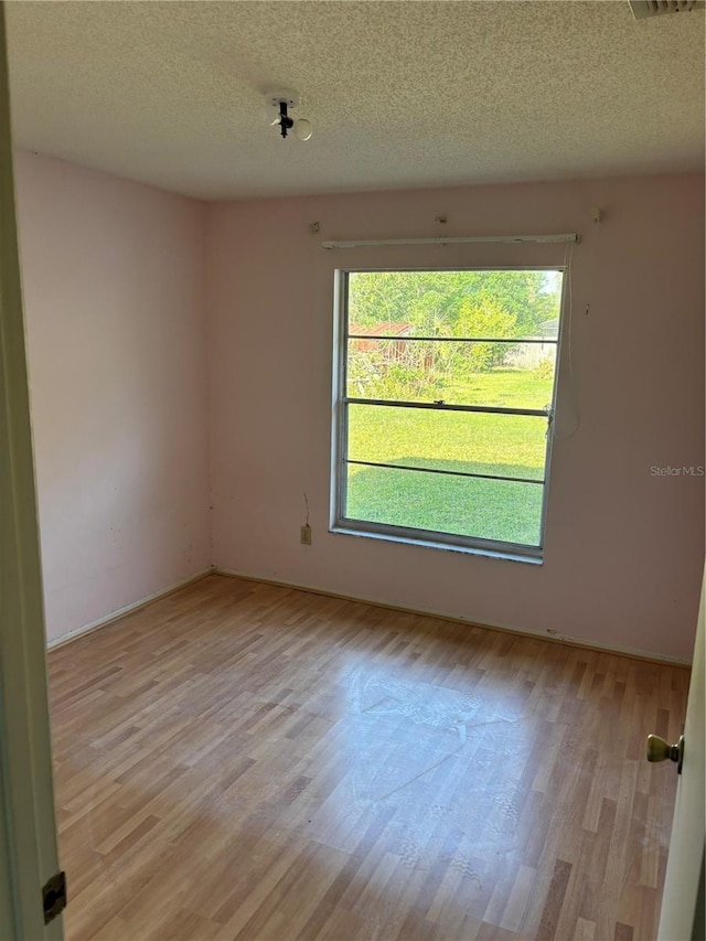 unfurnished room with baseboards, a textured ceiling, and light wood finished floors