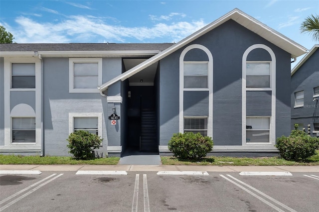 view of front of house featuring stucco siding and uncovered parking